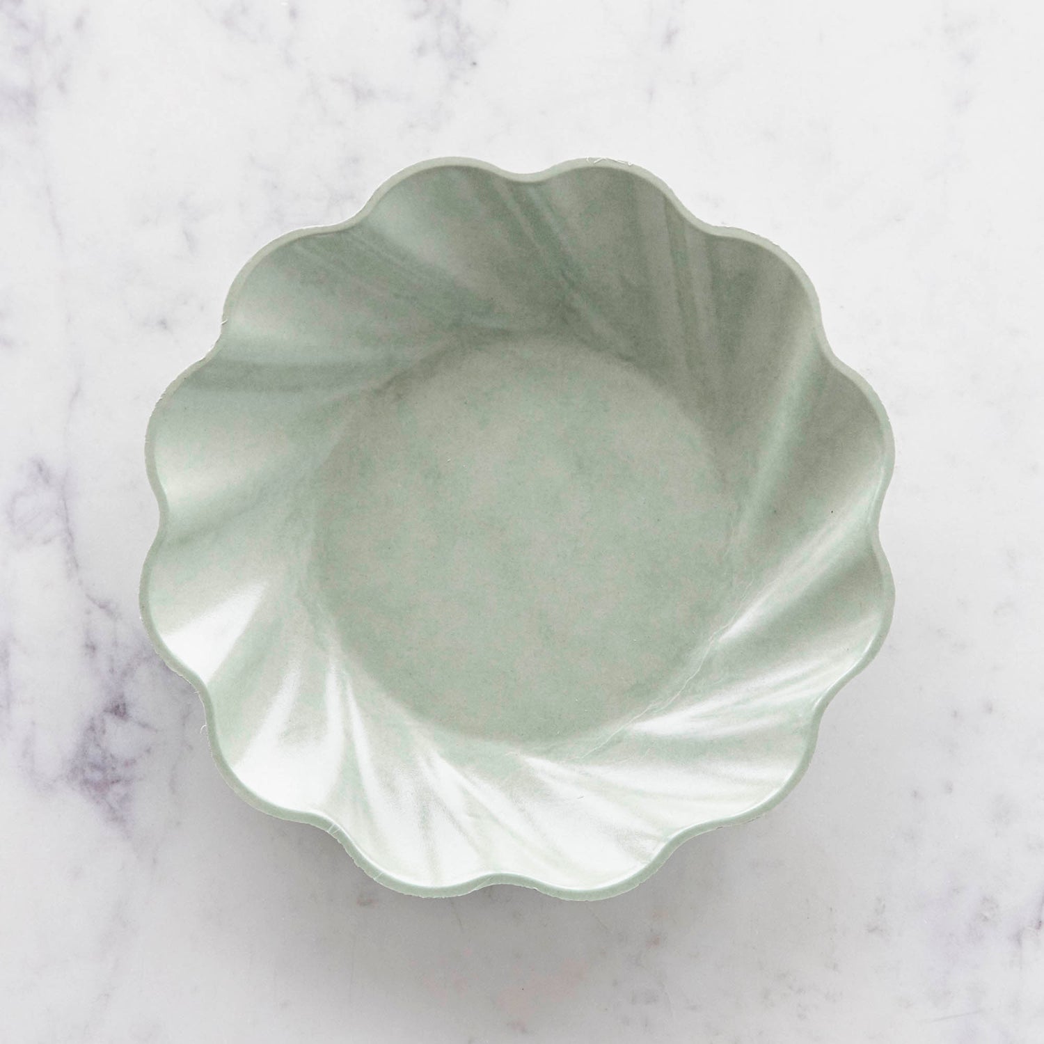 Three sturdy, Sophistiplate Wavy Eco Sage Plates stacked on top of each other.