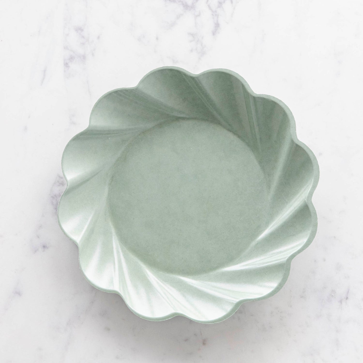 Three sturdy, Sophistiplate Wavy Eco Sage Plates stacked on top of each other.