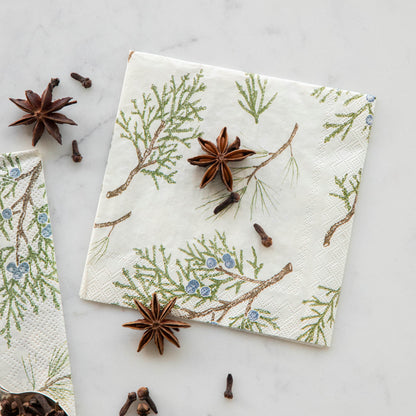 Close-up of a Juniper Sprigs Cocktail Napkin on a table, scattered with cloves and star anis.