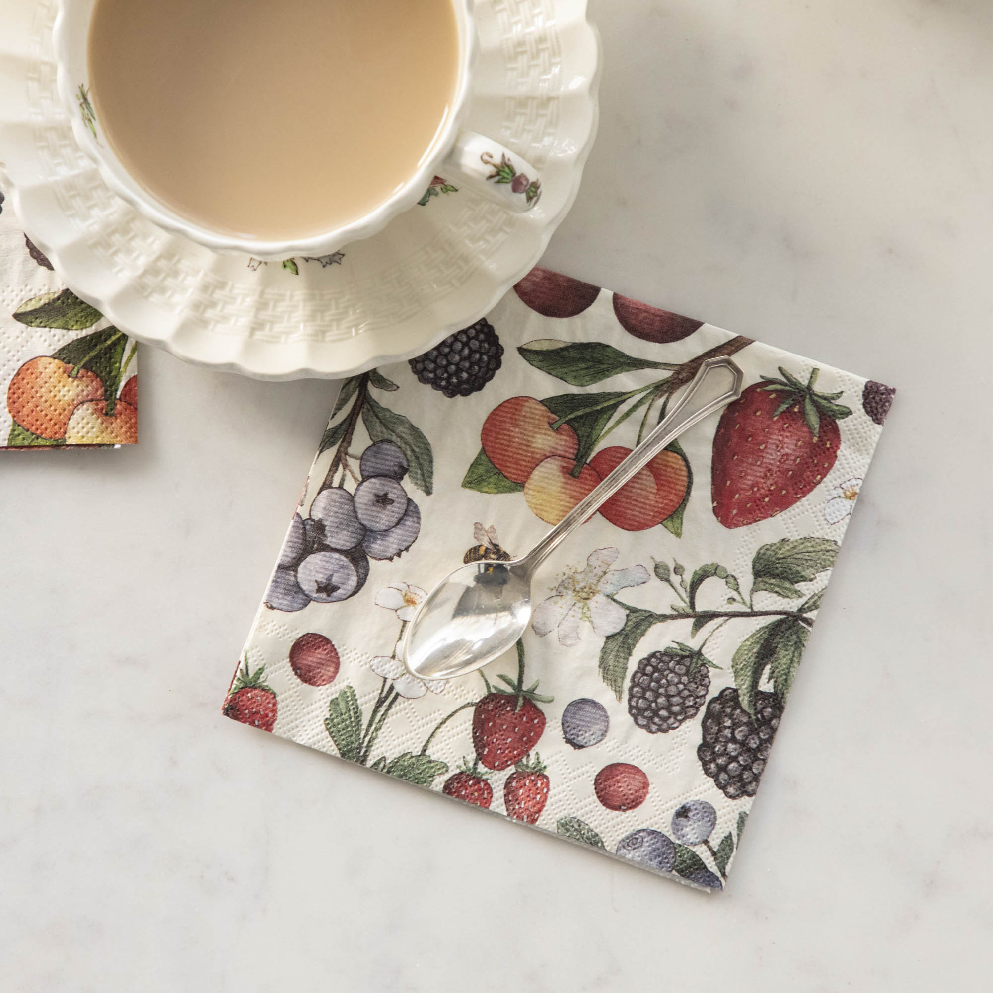 A Wild Berry Cocktail Napkin next to a cup of coffee.