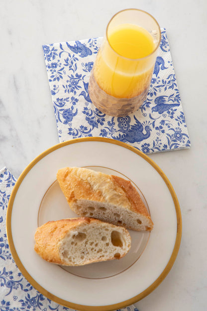 A plate of bread and a glass of juice on top of Blue Regal Peacock Guest and Cocktail Napkins by Hester &amp; Cook.