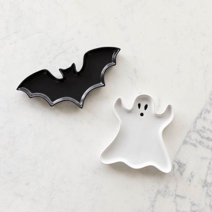 Stoneware Bat Shaped Dish and Stoneware Ghost Shaped Plate next to each other on a marble table.