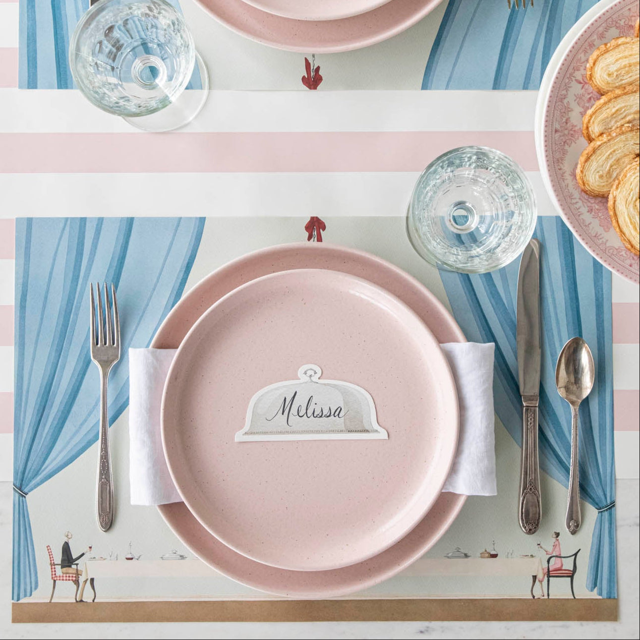 Table for Two Placemat under a place setting for one, featuring the Serving Dome Place Card resting in the center of the dinner plates.