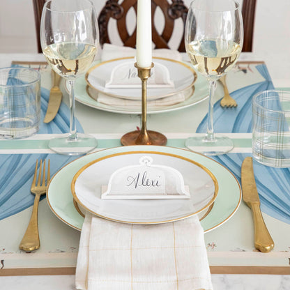 The Table for Two Placemat under an elegant place setting for two, featuring the Serving Dome Place Card in the center of the dinner plates.