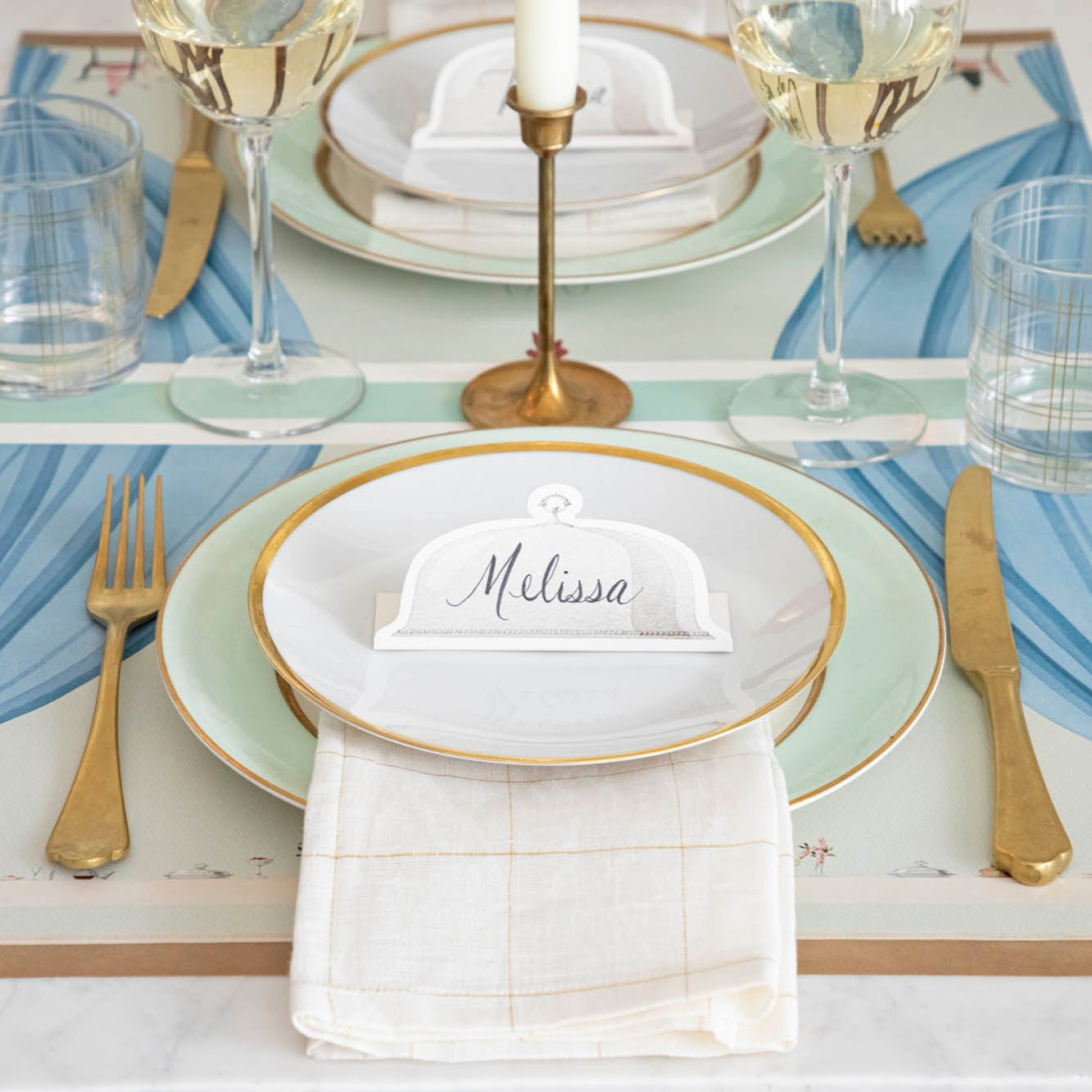 Serving Dome Place Card with &quot;Melissa&quot; written on it, resting on dinner plates on an elegant place setting.