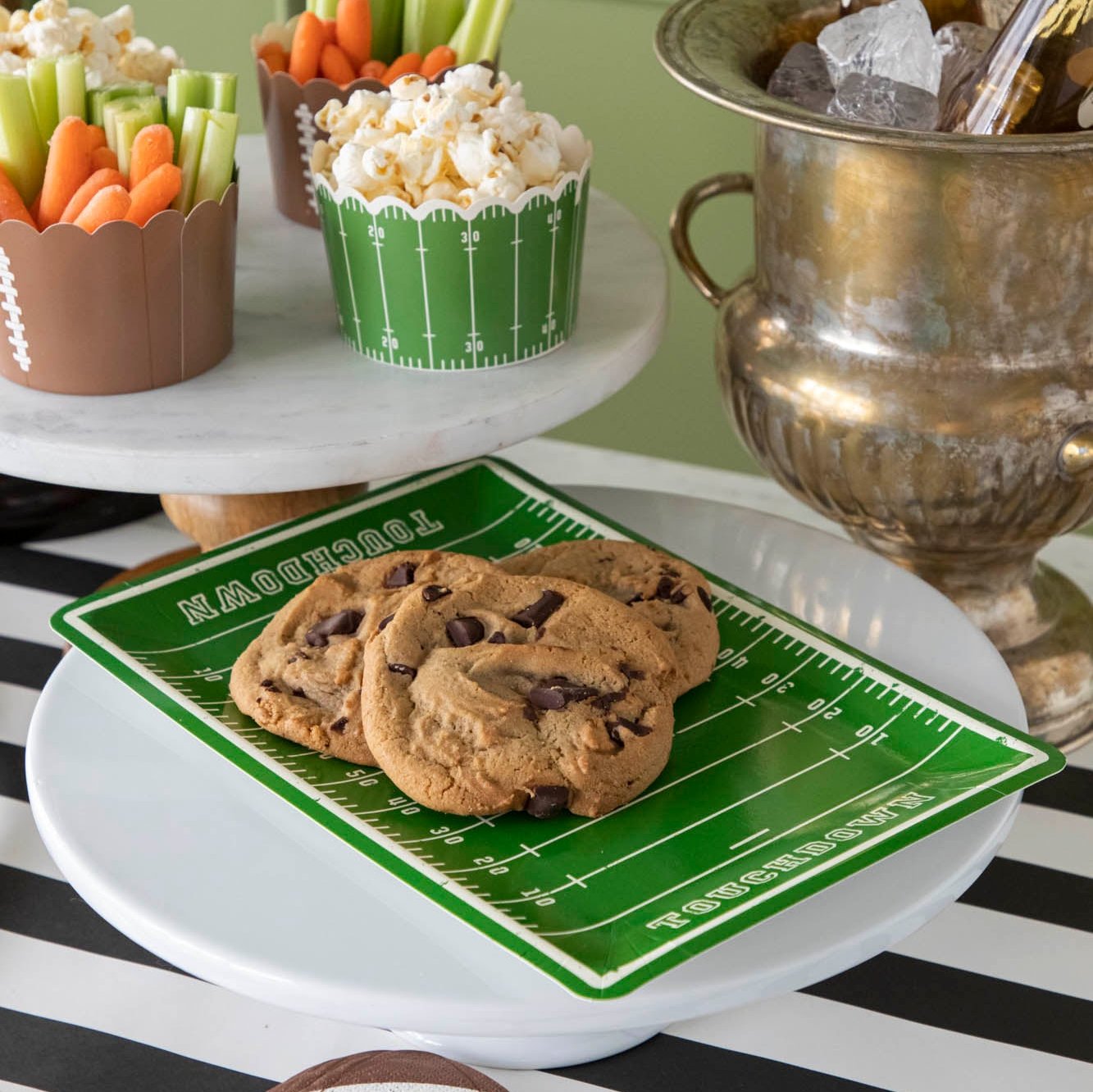 Cookies on top of a football field paper plate on a football themed table setting.