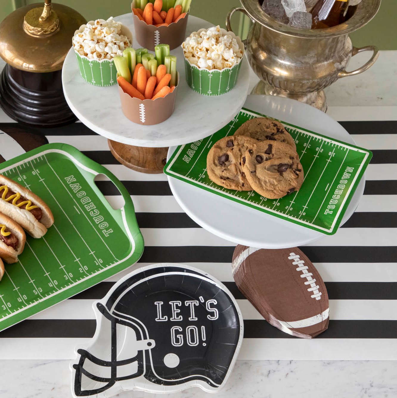 Football field paper plates with cookies on a football themed table setting with various snacks.