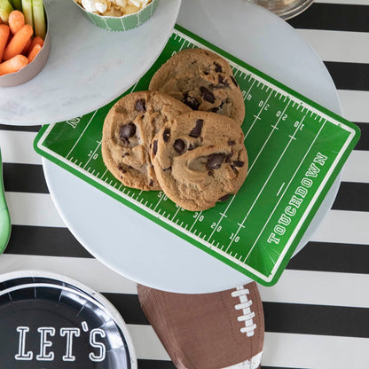 Cookies on top of a football field paper plate on a football themed table setting.