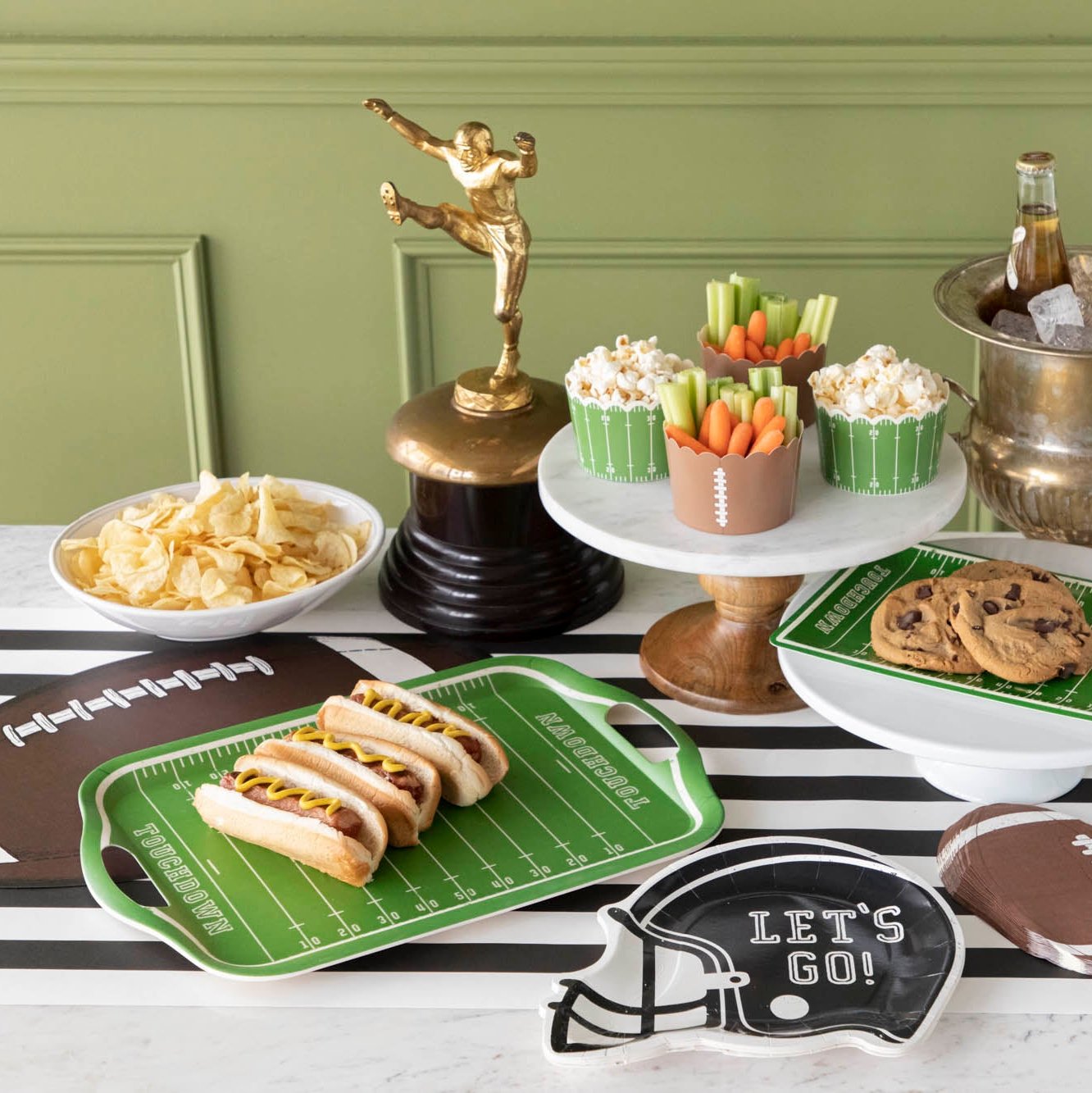 Football themed party with snacks, a trophy, football field tray and football helmet paper plates.