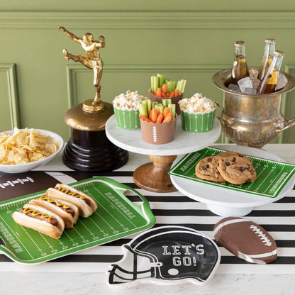 Football themed table set up with various snacks and football themed paper tableware.