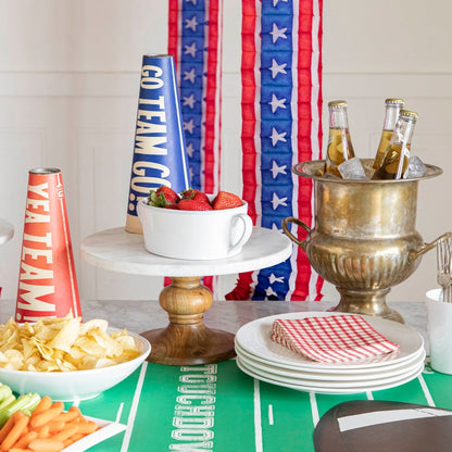 Football themed table setting with various game day snacks and decor including a Touchdown football field runner.