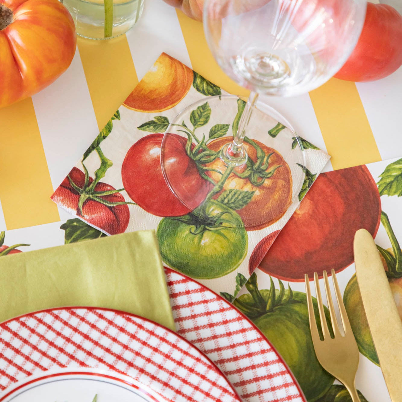 Tomato Cocktail Napkin under a glass behind a place setting.