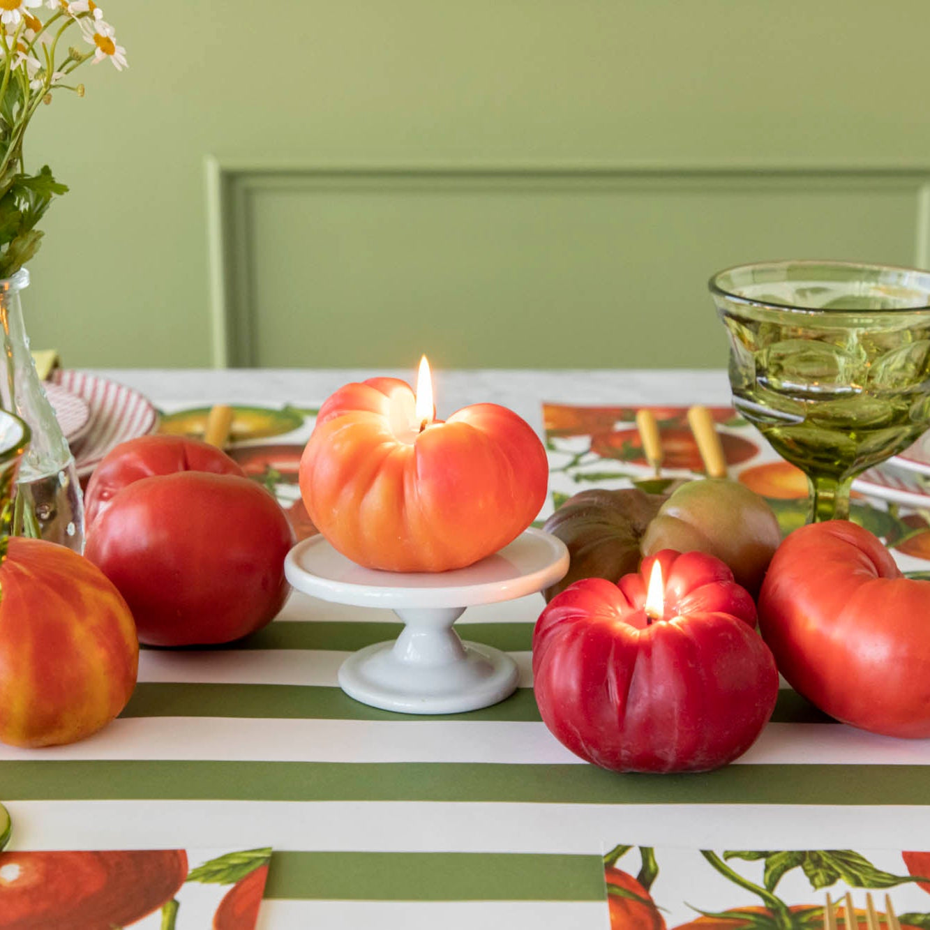 Lit Tomato Candles in the center of a summery, tomato themed table.