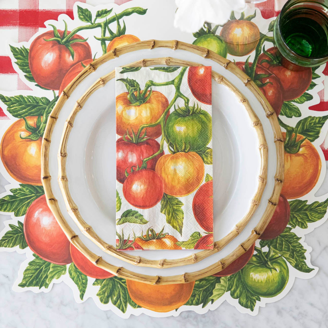 Tomato Guest Napkin centered on dinner plates, on a place setting for one.