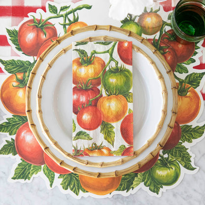 Tomato Guest Napkin centered on dinner plates, on a place setting for one.