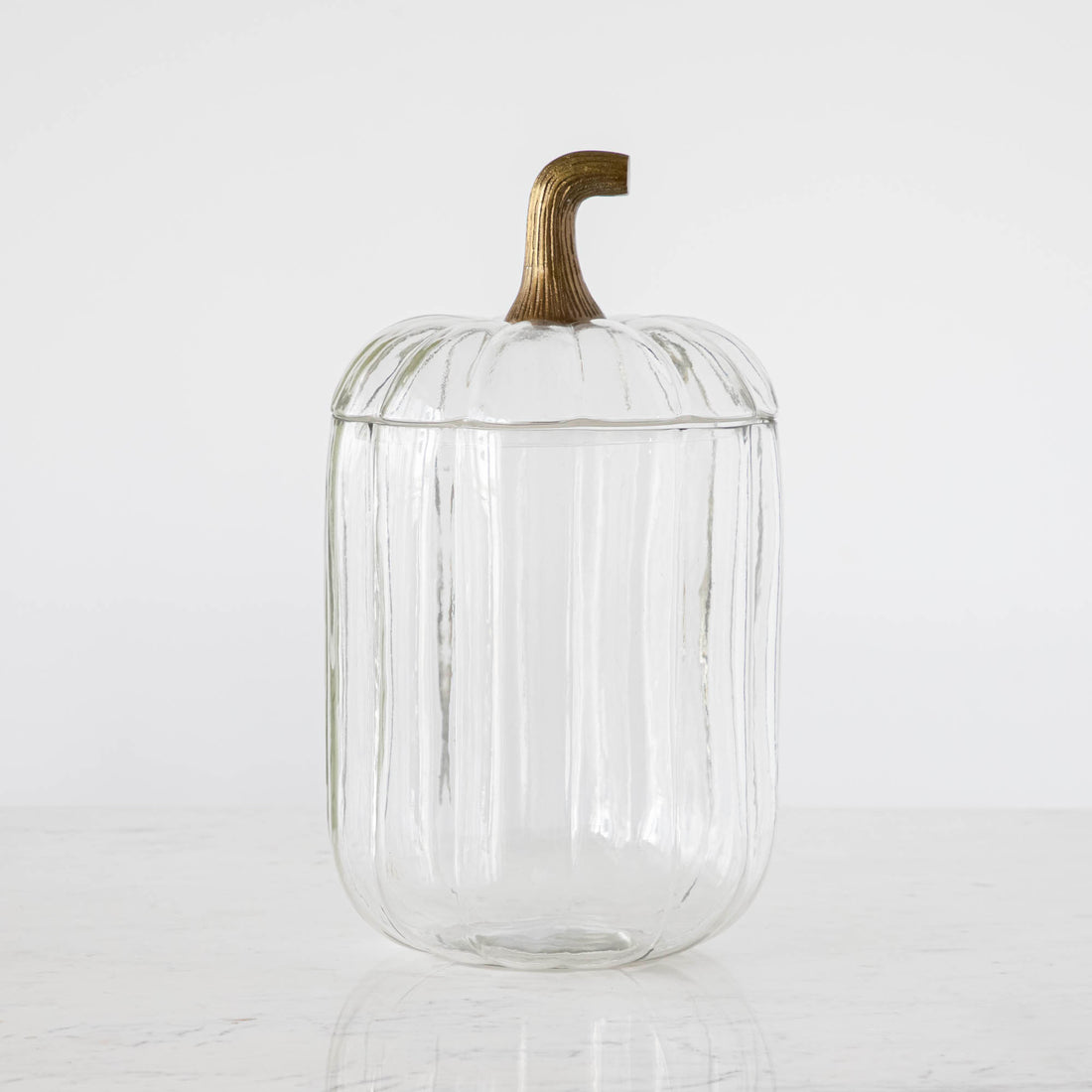 A small Translucent Pumpkin Terrarium with an antique bronze stem lid on a marble table.