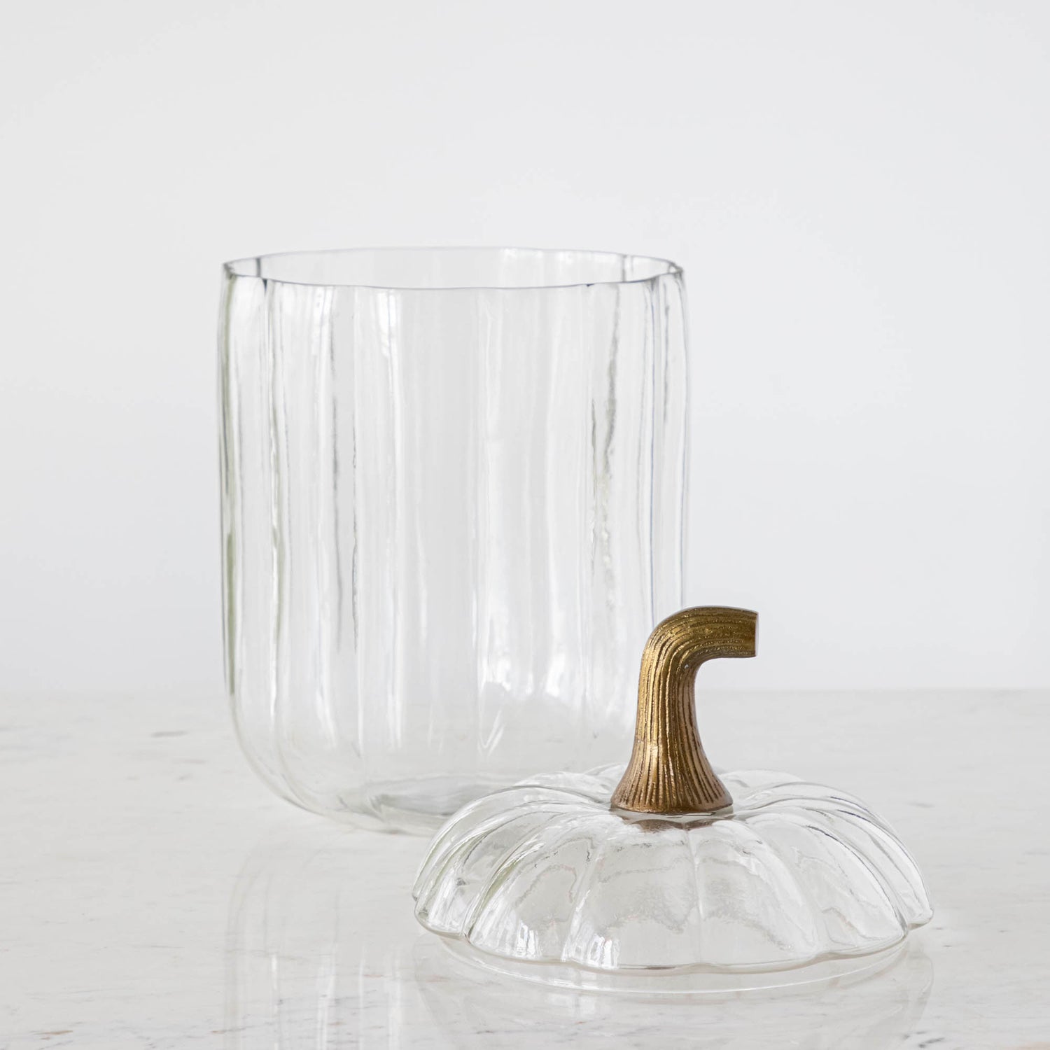 A large Translucent Pumpkin Terrarium with an antique bronze stem lid next to it, on a marble table.