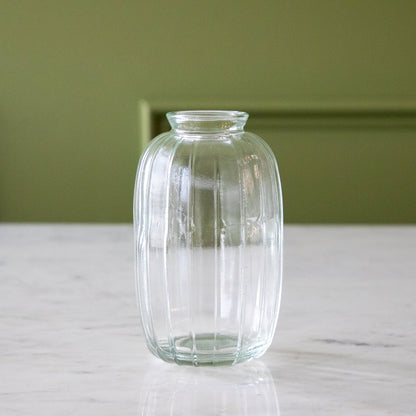 A clear glass bud vase with a ribbed design.