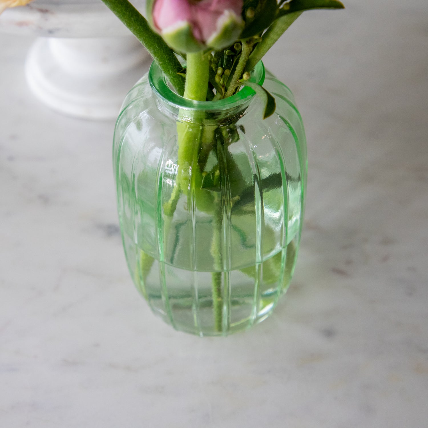 A top down view of the Green Glass Bud Vase with flower in it.