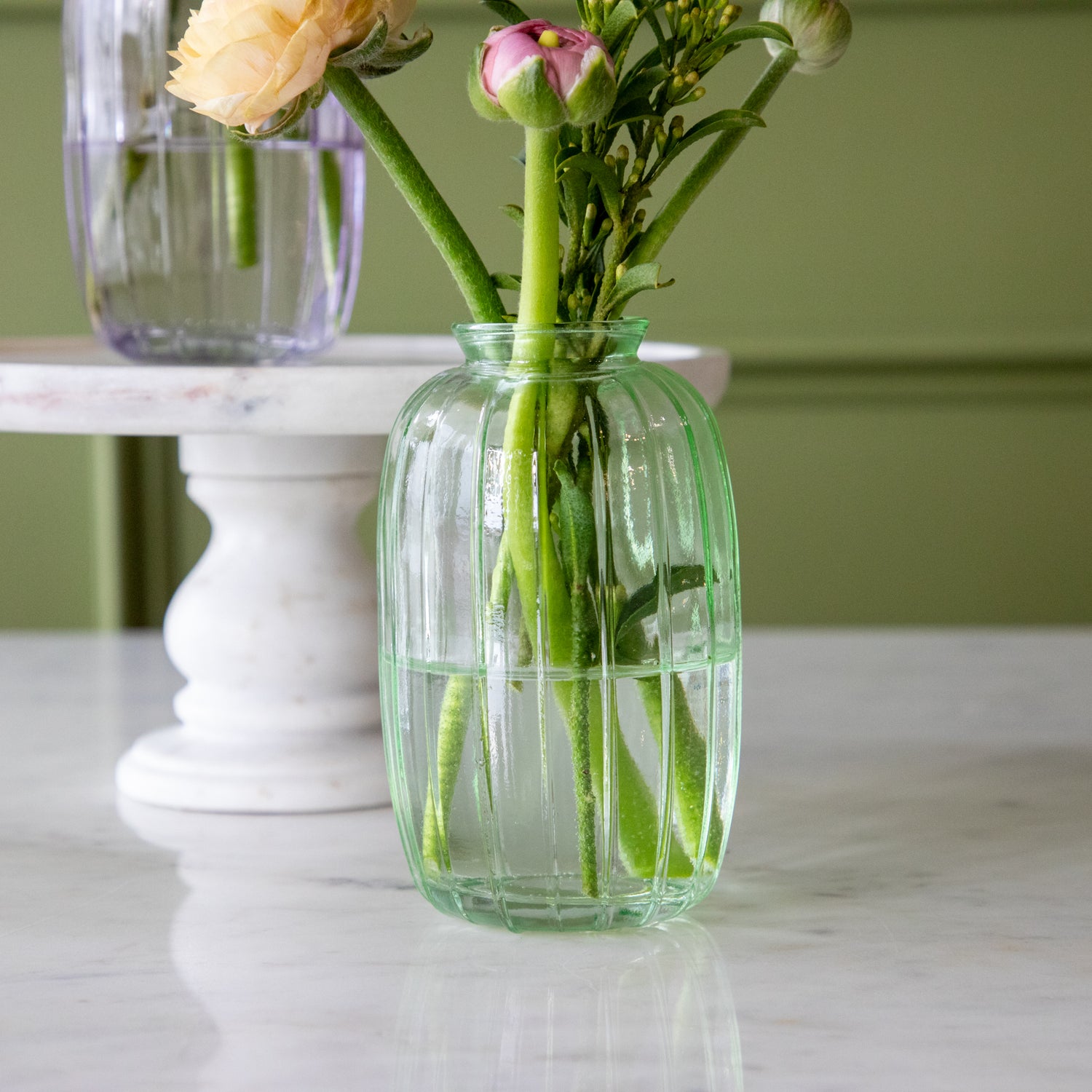 The Green Glass Bud Vase with spring flowers and water in it.