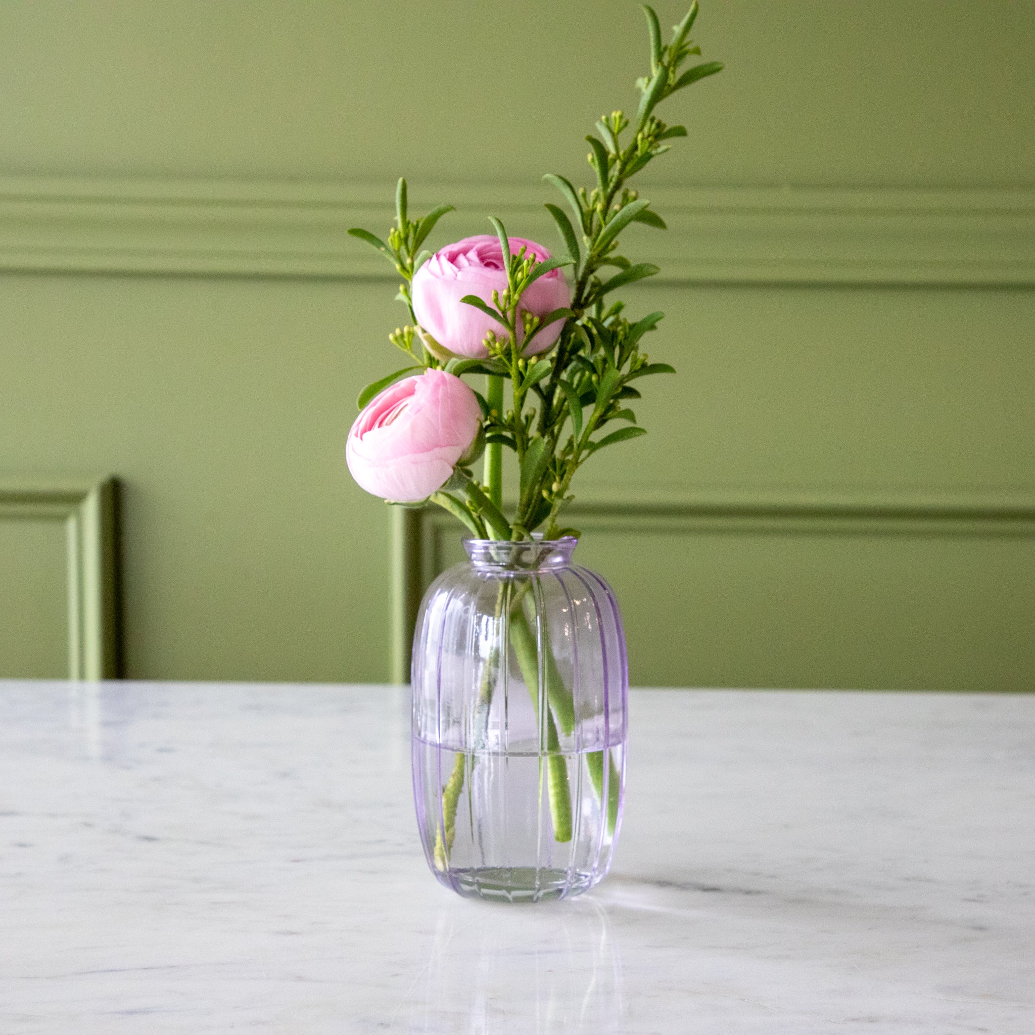 The Lilac Glass Bud Vase with spring flowers in it.