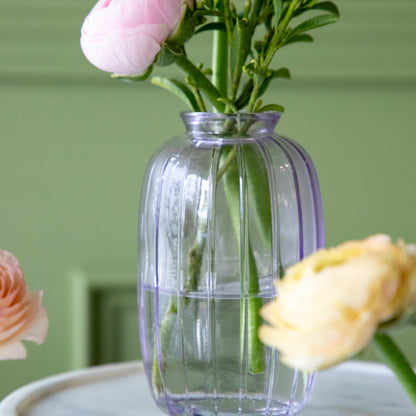 The Lilac Glass Bud Vase with flowers and water in it.