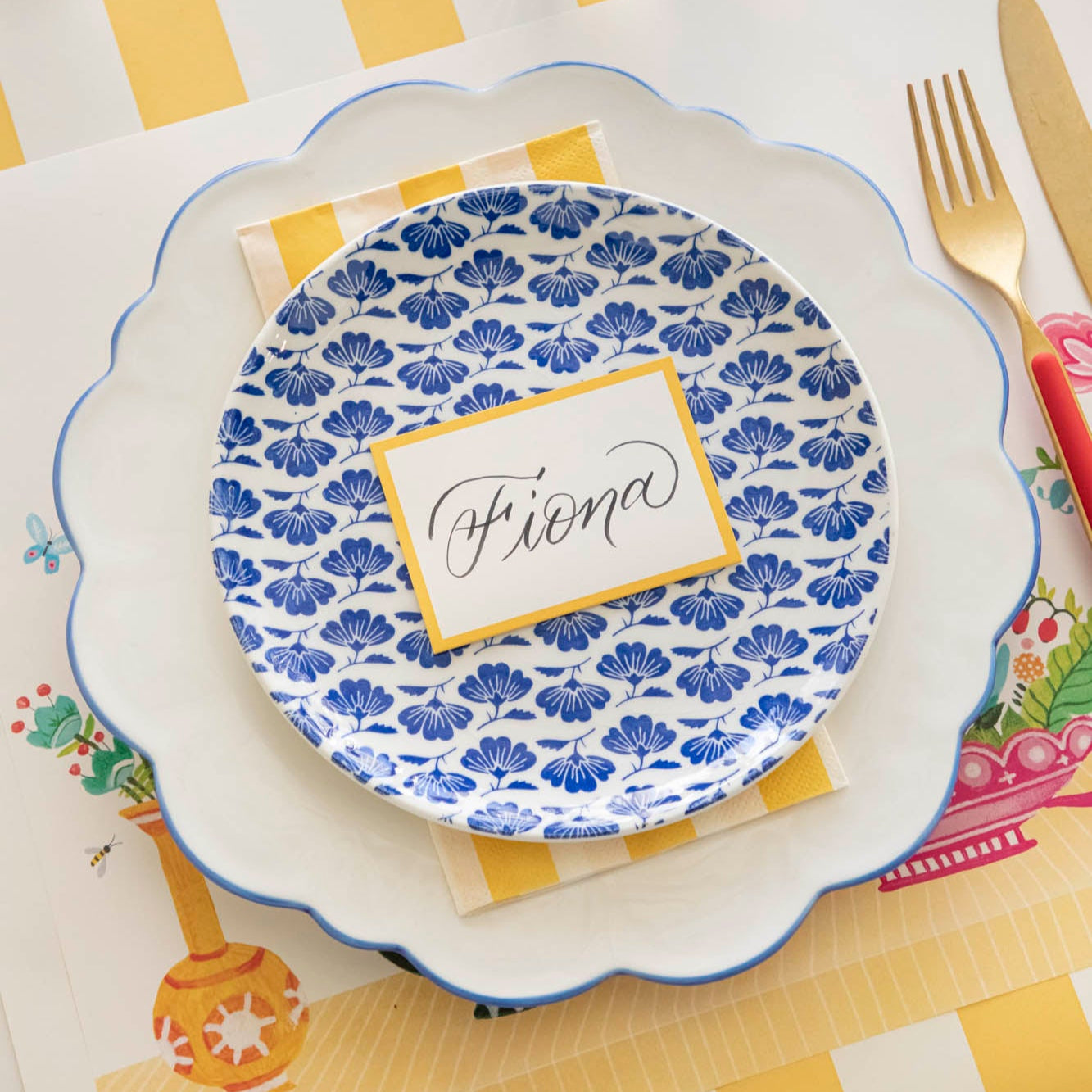 Marigold Classic Stripe Guest Napkin in between two plates on a vibrant, floral place setting.