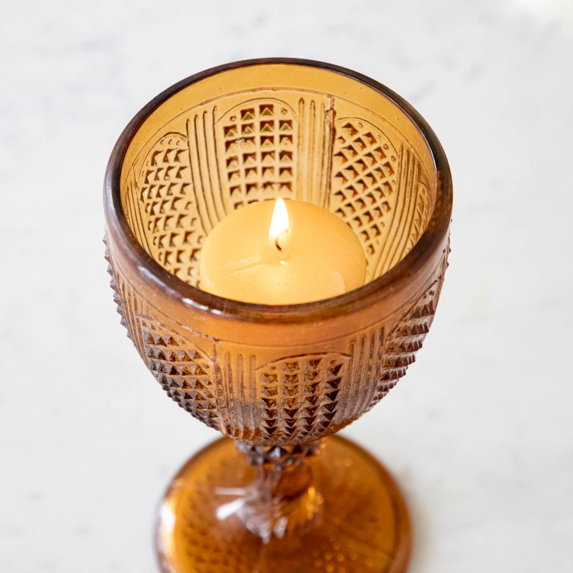 Inside view of a Vintage amber votive holder with a lit candle inside.