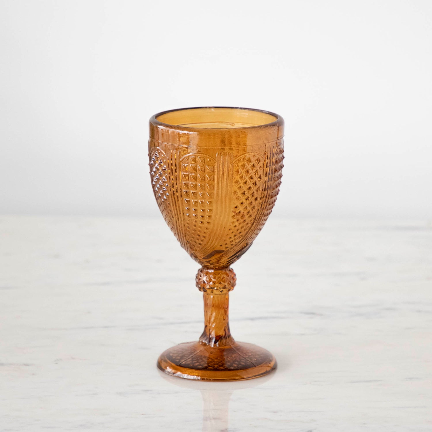 Vintage amber stemmed votive holder on a marble table.