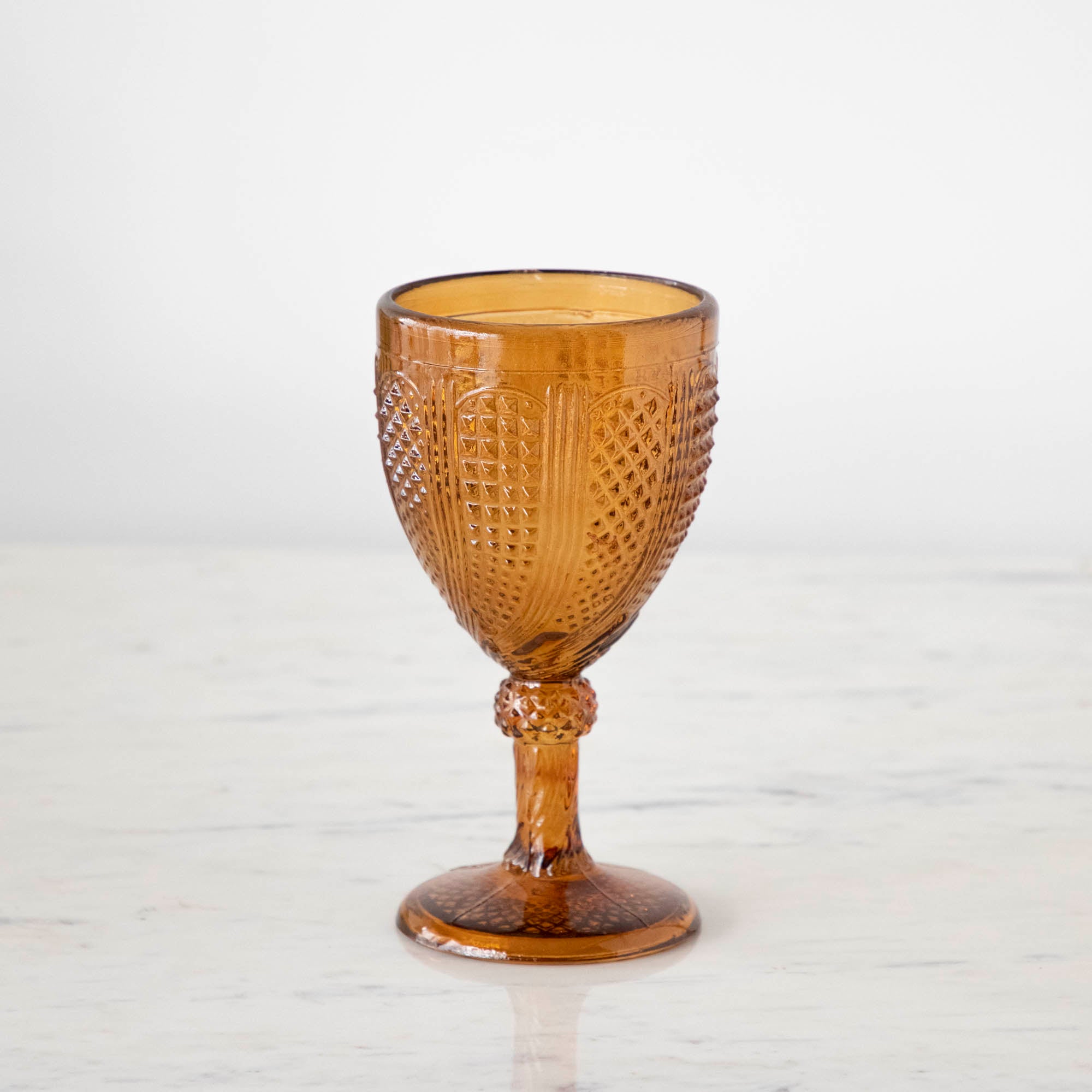 Vintage amber stemmed votive holder on a marble table.