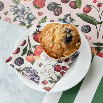 Wild Berry Cocktail Napkin on a plate with a blueberry muffin on top.