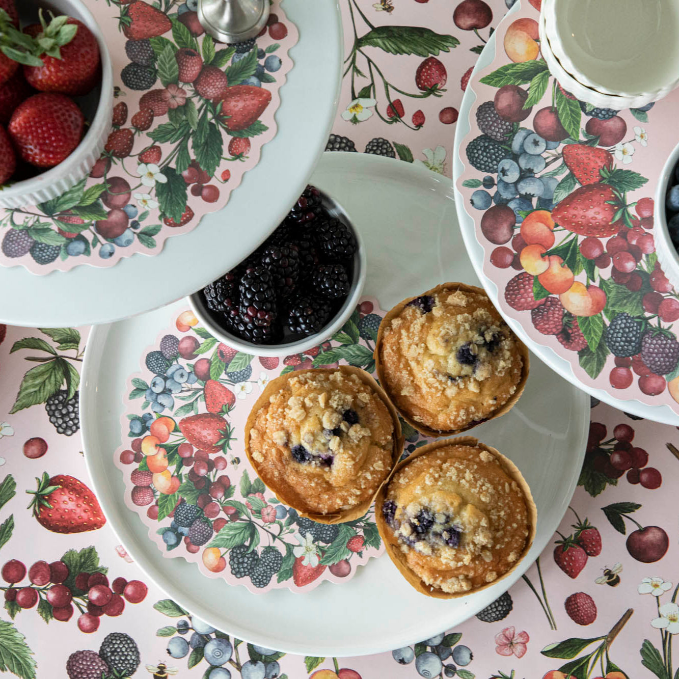 Wild Berry Serving Paper on a cake stand beneath cups of berries and muffins.