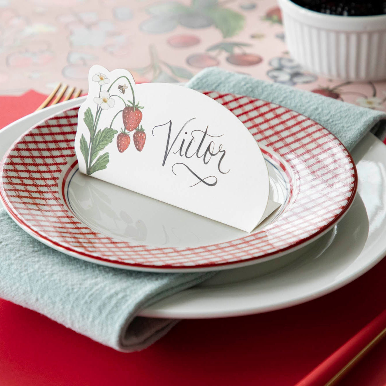 Wild Berry Place Card with &quot;Victor&quot; written in script, centered on dinner plates on a berry themed place setting.