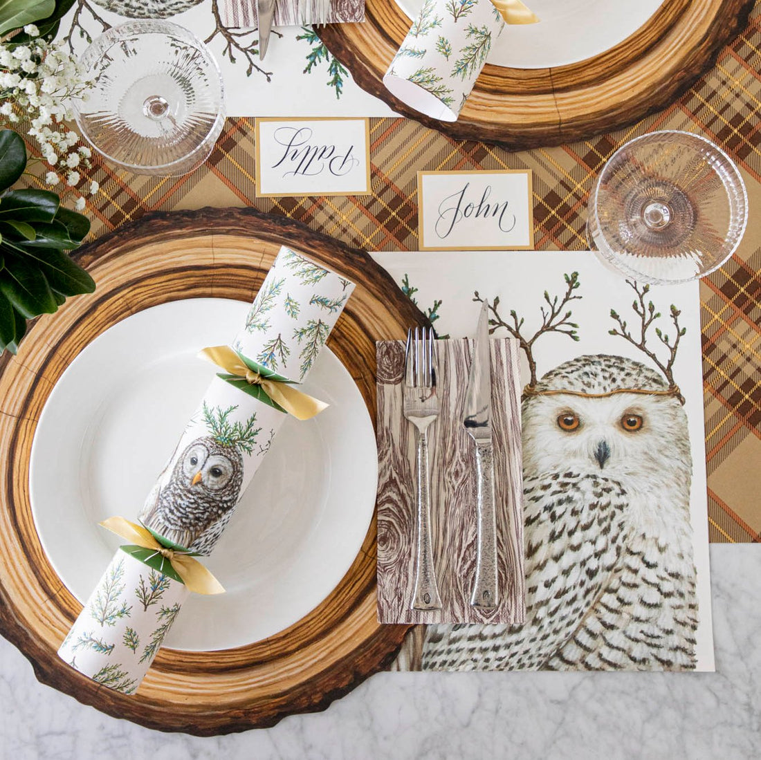 Die-cut Wood Slice Placemat with a white plate and Winter Owls Cracker on top and Oak napkins with silverware and an Autumn Plaid runner and Winter Owls Placemat  underneath.