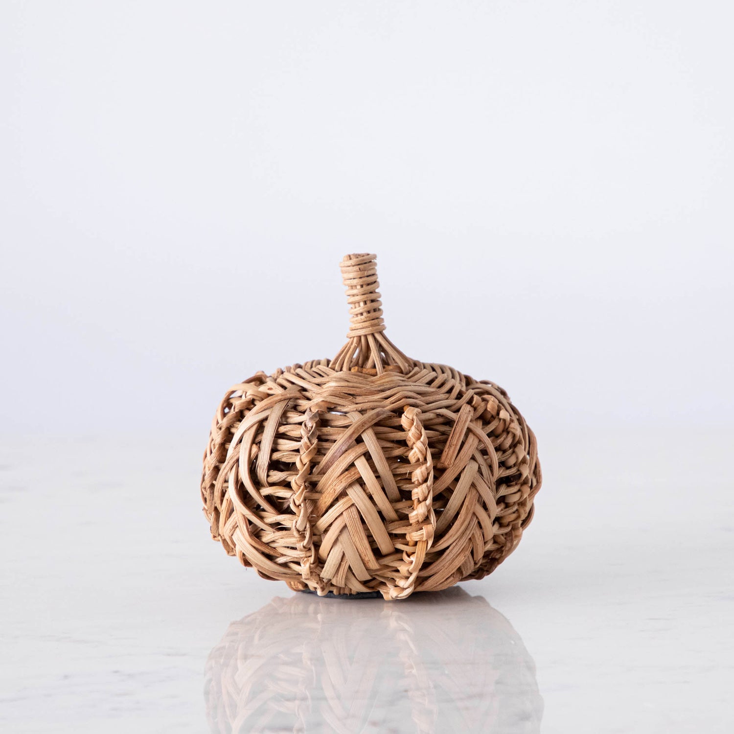 A small woven pumpkin on marble.