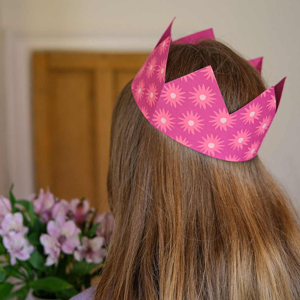 A woman wearing the East End Press Pink Paper Party Crown on her head.