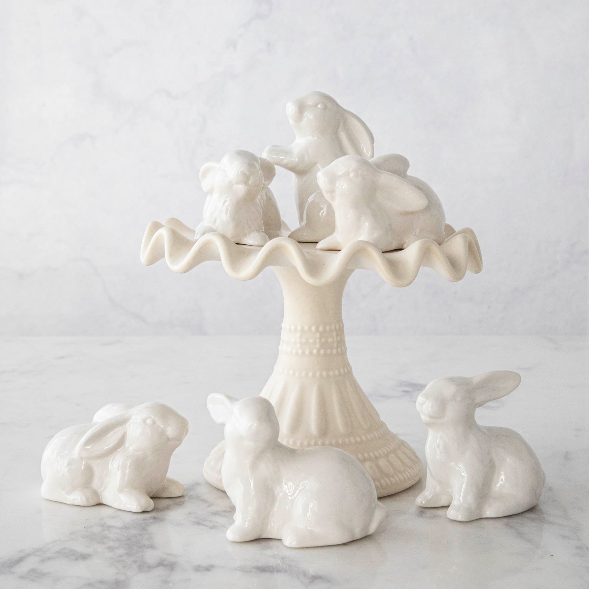 A group of Creative Co-Op Ceramic Bunnies, Set of 6, on a cake stand.