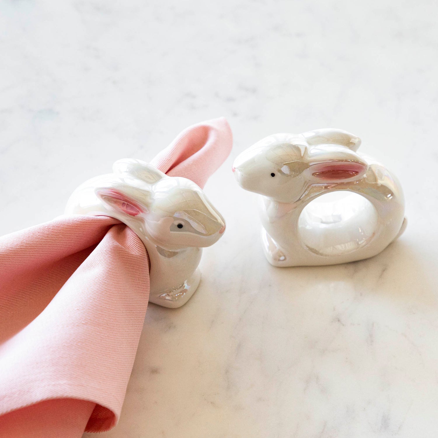 Two Glitterville Bunny Napkin Rings with a springy touch on a napkin.