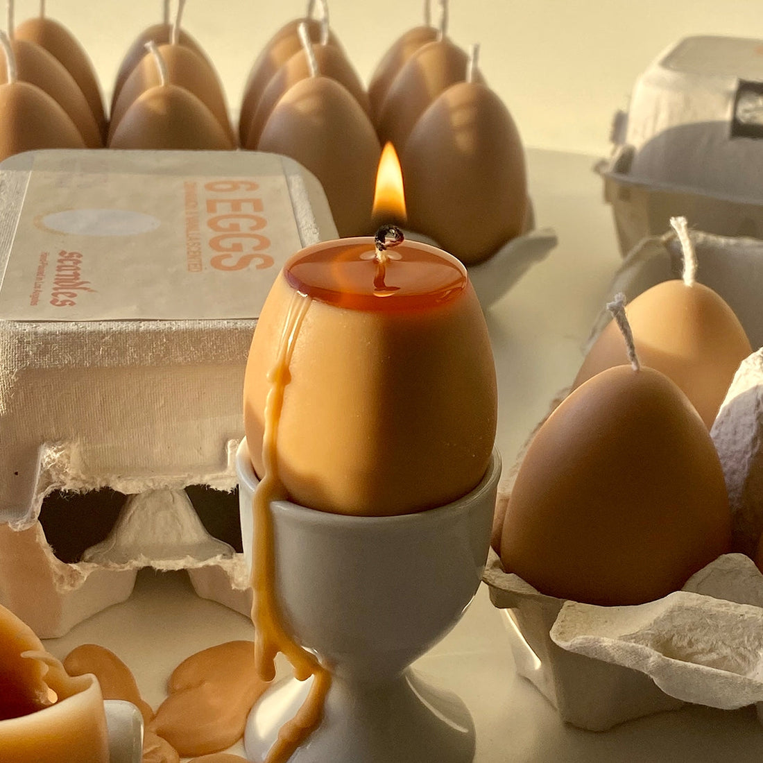 Close up of egg candle burning in an egg cup in the foreground with lots of the egg candles in the background. 