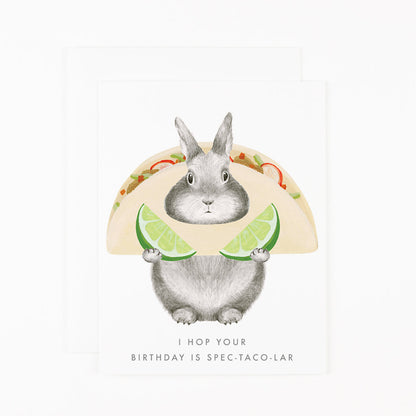 A Spec-Taco-Lar card by Dear Hancock, featuring a cute bunny holding a taco, made in the United States of America. This card is printed on soft white paper, creating a high-quality and visually pleasing design. Perfect.