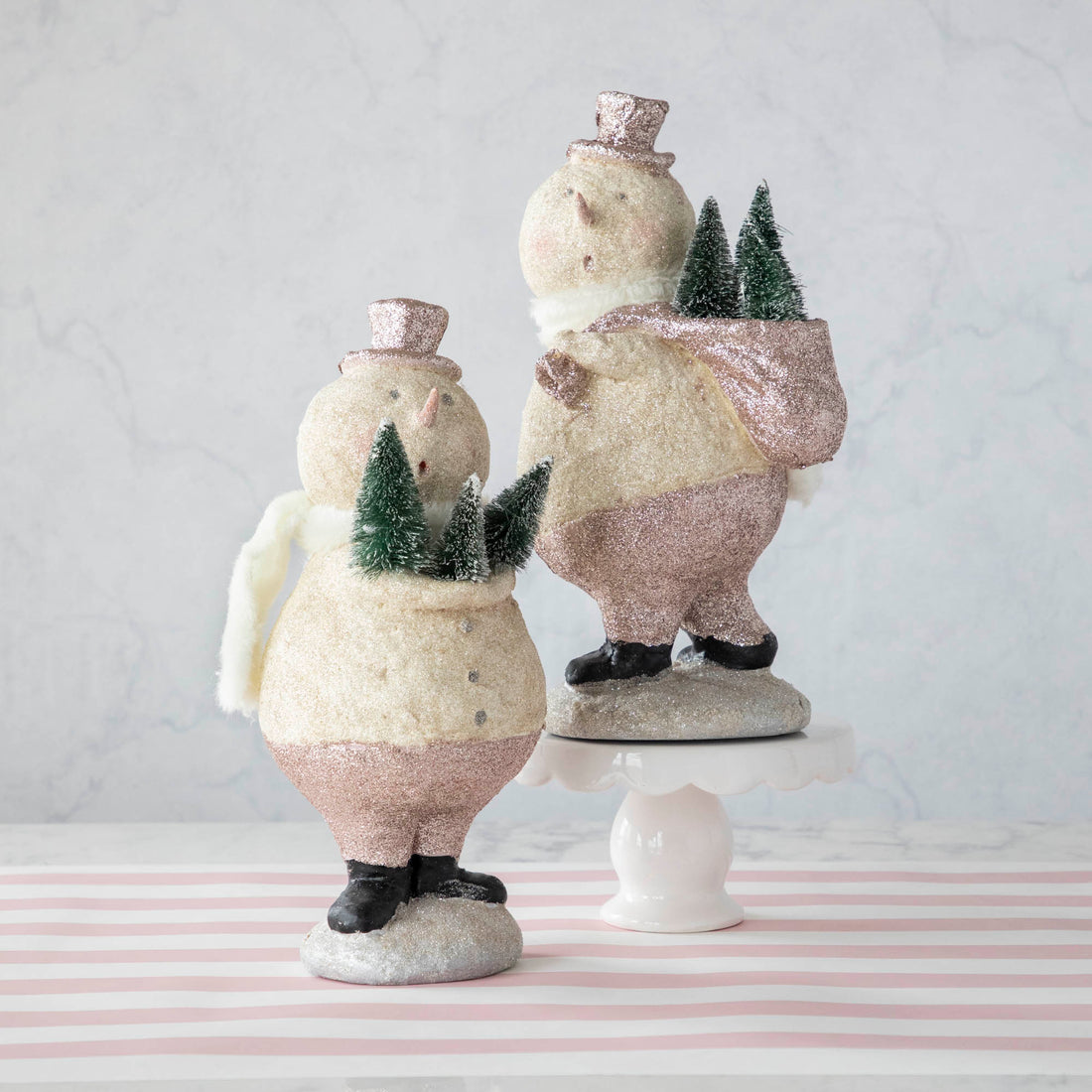 Two Sparkle Snowman figurines from Glitterville on top of a table spread holiday cheer.