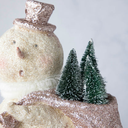 A close up of the Sparkle Snowman carrying snowy trees in a sack on its back.