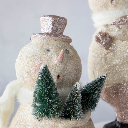 Two Sparkle Snowman figurines from Glitterville on top of a table spread holiday cheer.