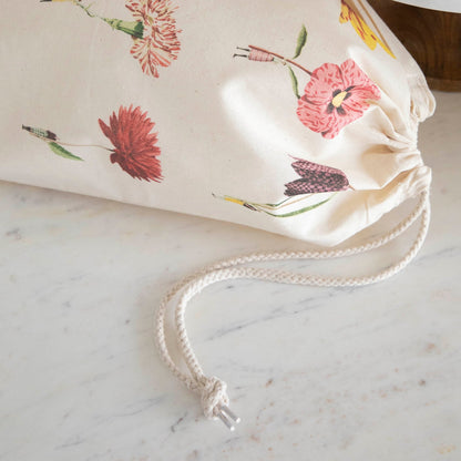 A close-up of the In Bloom Medium Laura Stoddart Drawstring Bag, cinched closed by a white rope.