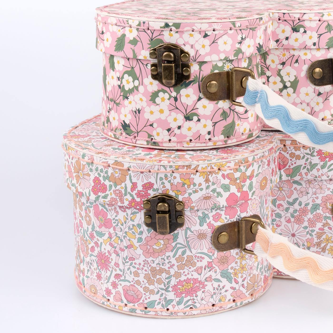 Two different sized heart-shaped suitcases made from stitched card with lamination. The smaller case can be stored inside the larger.  Each suitcase features a different Liberty floral print design, with pink tones, on the outside.