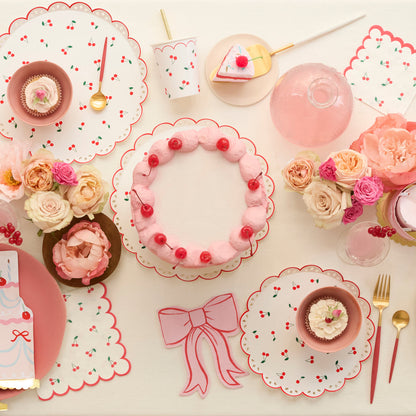 Lifestyle of various Meri Meri paper plates, napkins and cups on a table with a cake. 