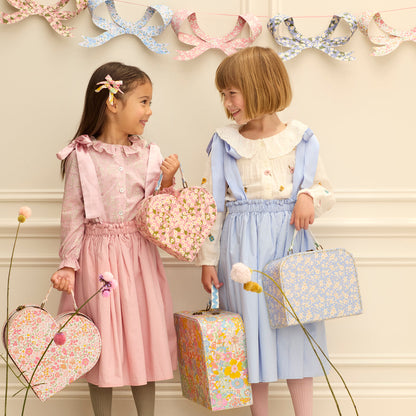 Two children holding Meri Meri x Liberty suitcases. 