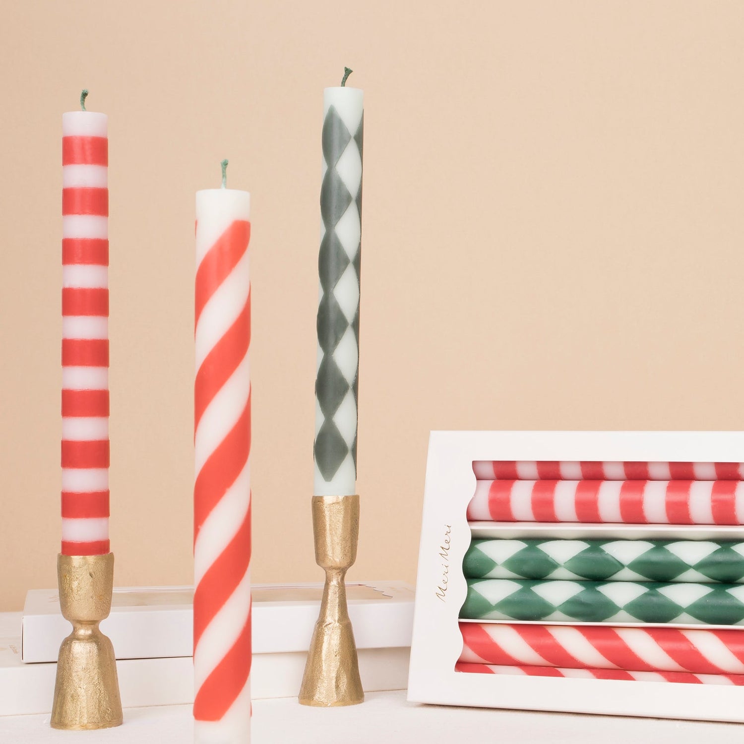 Festive Stripe Taper Candles in gold taper candle holders with the boxed set beside them.