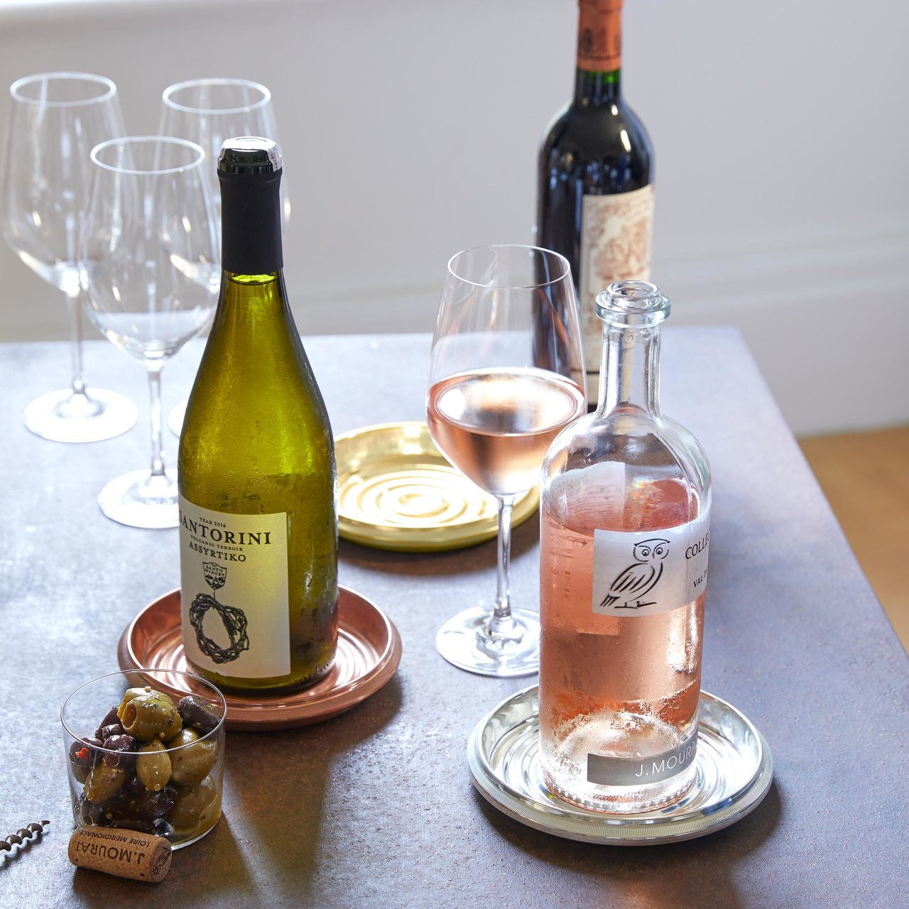 Brass Bottle Coaster on a table with glasses and bottles of wine. 