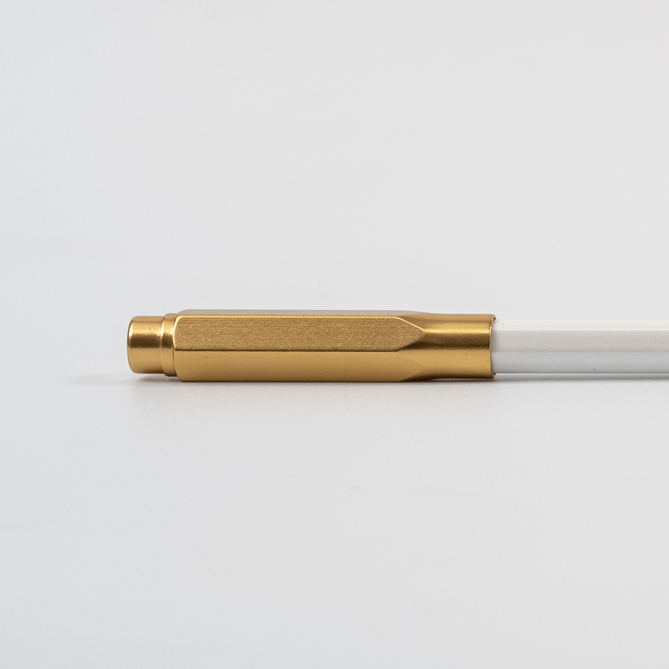 A black, gold, and silver Blackwing Point Guard sits on a white surface next to a Blackwing pencil.